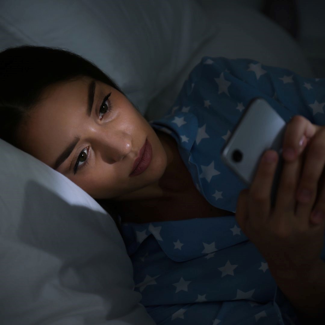 Chica con móvil en la cama. Adicción al móvil